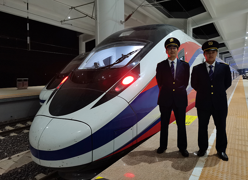 劉銀能（右一）與中國師父鄔俊鴻在動車組前合影。受訪者供圖